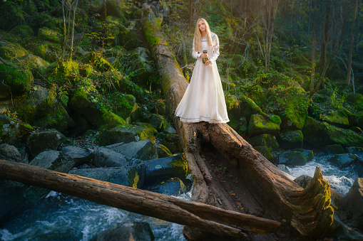 Beautiful young woman in a white dress walk in the middle of a forest