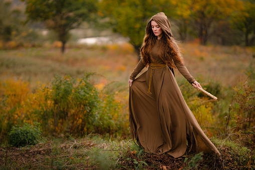 Redhead woman in green dress walking in fantasy fairy tale forest