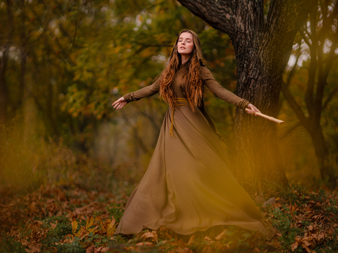 Redhead woman in green dress walking in fantasy fairy tale forest