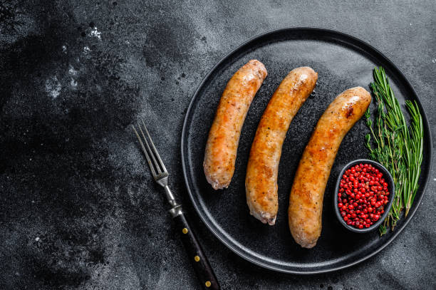 istock Sausages fried with spices and herbs on a plate. Top view. Black background. Copy space 1333186794