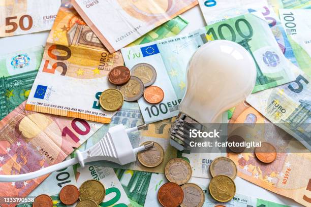 Electric Plug And Light Bulb On Euro Banknotes And Coins Stock Photo - Download Image Now