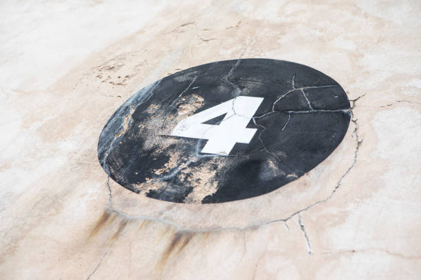Number 4 in a black circle, painted onto a rough an weathered, sand-coloured wall