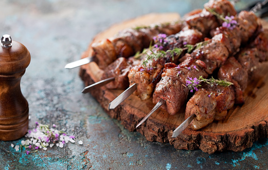 Shish kebab, Grilled lamb meat skewers with spices and oregano flowers on a wooden board, selective focus
