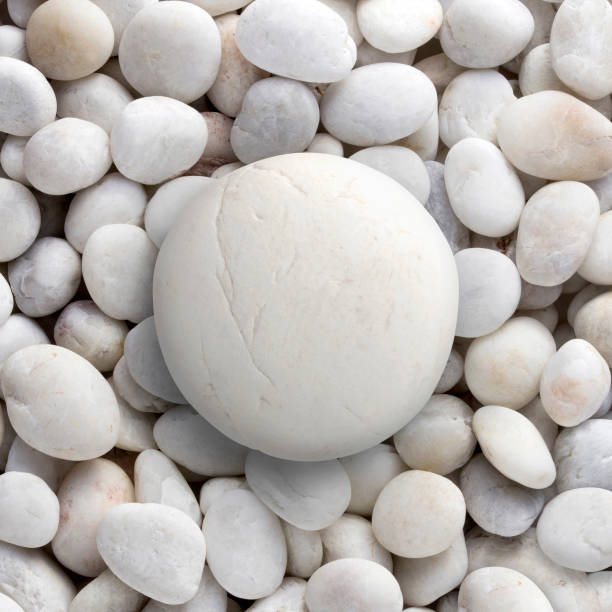 Big rock on small rocks background or texture. Circle shape of big pebble on small peddles. White round big pebble, stone, rock laid on pile of nature pebbles, stones, rocks with copy or text space.
