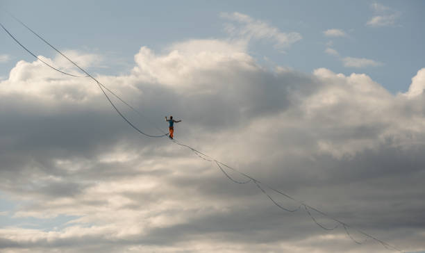 istock A tightrope walker walks along the highline. Dramatic cloudy sky in background 1333194802