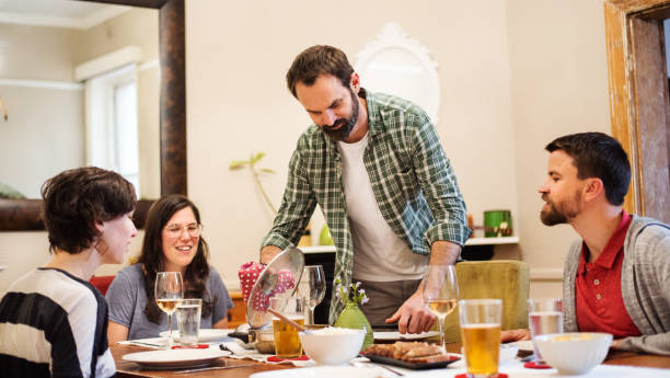 istock Smiling man serving food during a dinner party with friends 1333197595