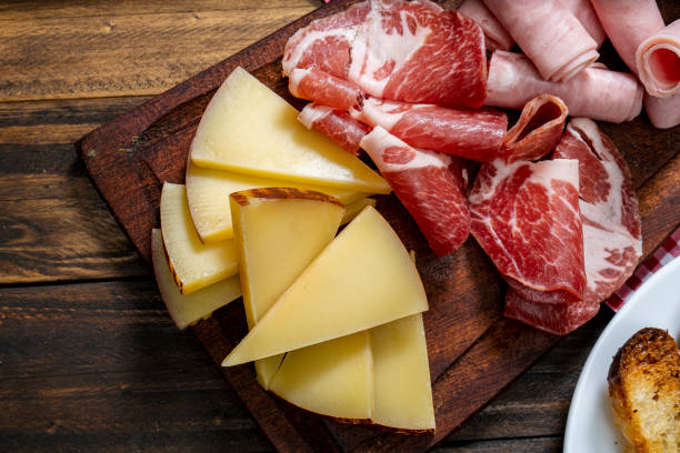 Cheese board and cold cuts on a wooden table. Bird eye view. Cheese board and cold cuts on a wooden table. Zenithal or bird eye view. prosciutto brie stock pictures, royalty-free photos & images