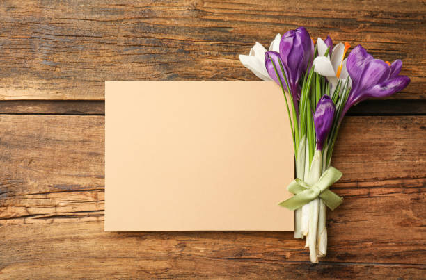 istock Beautiful spring crocus flowers and blank card on wooden table, flat lay. Space for text 1333204932