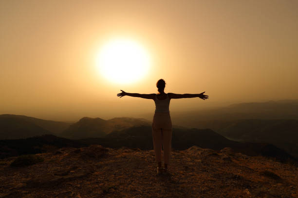 istock Woman silhouette outstretching arms at sunset 1333205105
