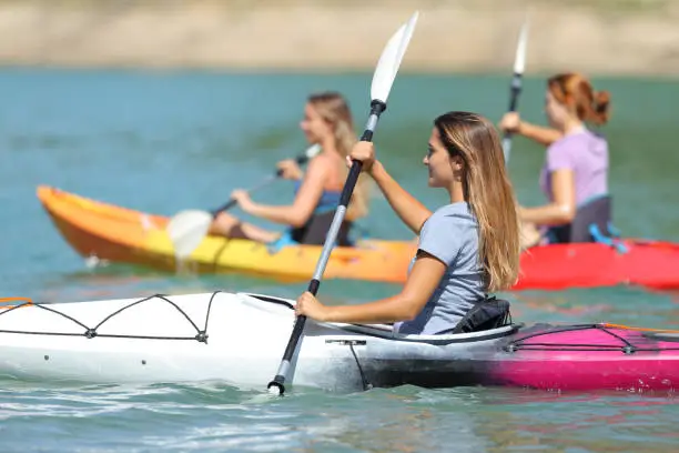 Friends rowing in kayaks in a lake