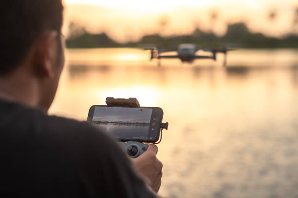 The drone pilot's hand is holding a remote control to control the drone. For taking high-angle photos and videos The drone pilot's hand is holding a remote control to control the drone. For taking high-angle photos and videos remote controlled stock pictures, royalty-free photos & images