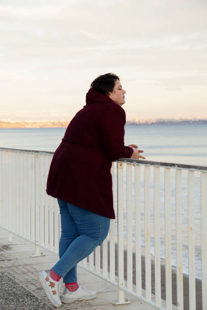 istock Young overweight woman standing alone on the beach 1333216739