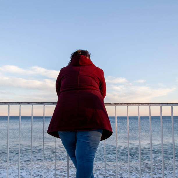 istock Young overweight woman standing alone on the beach 1333216751