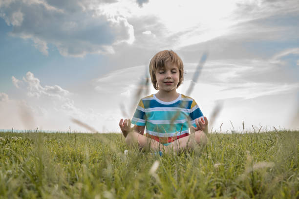 Little boy with eyes closed  practices yoga outdoors