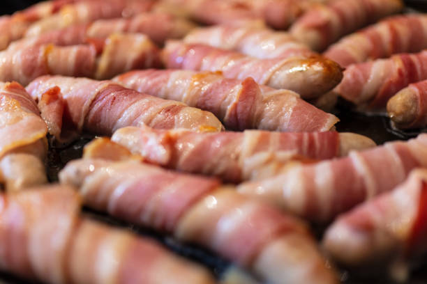 Macro close up of sausages wrapped bacon or Pigs in Blankets cooking stock photo