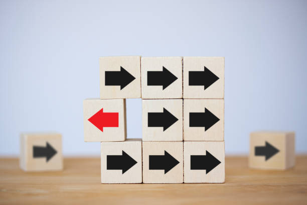 istock Wooden block with red arrow facing opposite direction black arrows, think different, leader, individual and standing out of the crowd concept 1333218045