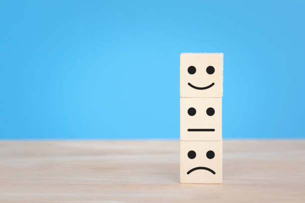 istock Wooden blocks showing face icon emotion, happiness, sad, sadness, different thinking isolated on blue background. 1333218050