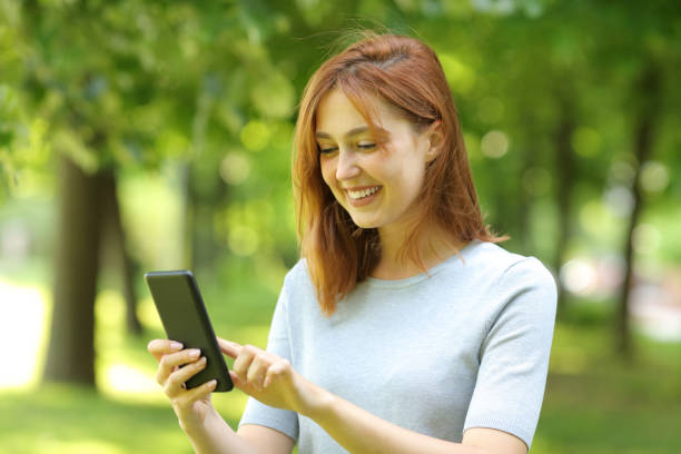 istock Happy female using smart phone walking in a park 1333218308