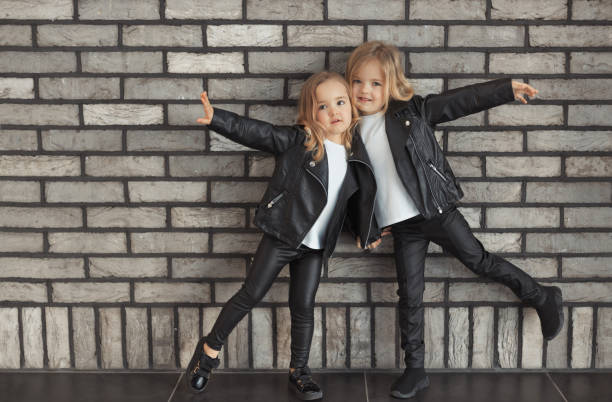 istock Two pretty sisters in same outfits: white t-shirts, leather black jackets and leggings 1333222302