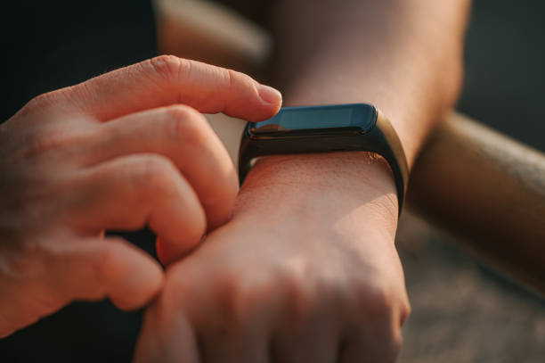 close up asian chinese adult woman hand checking her heartbeat with fitness tracker after home workout in the morning - leaning forward fotografías e imágenes de stock