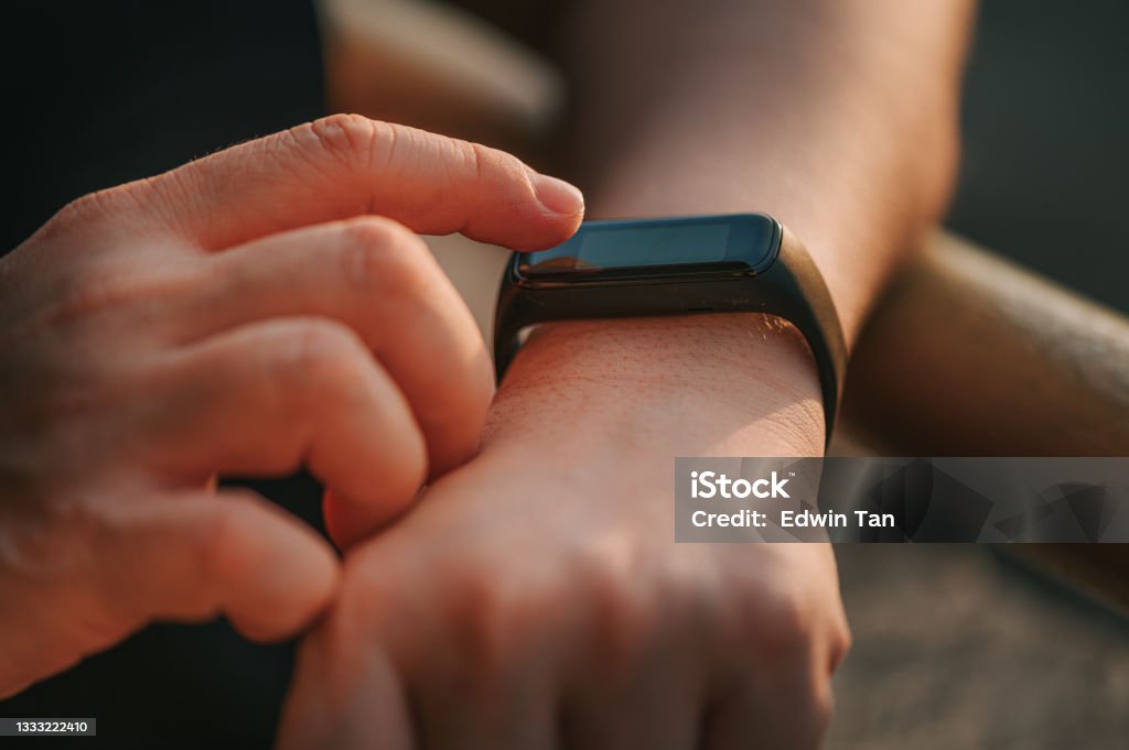close up Asian chinese adult woman hand checking her heartbeat with fitness tracker after home workout in the morning Smart Watch Stock Photo