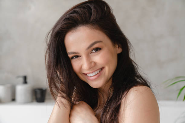 jovem mulher branca bonita com cabelos castanhos brilhantes e lisos tocando-o para um bom volume. cuidados com o cabelo e a pele, conceito de tratamento de beleza - applied science - fotografias e filmes do acervo