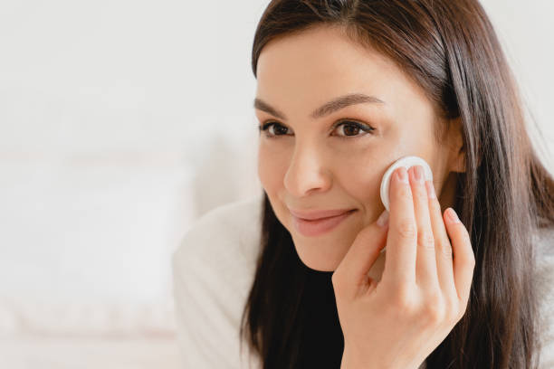 istock Young beautiful woman using applying cream softening moisturizer with cotton pad on her face, removing cosmetics. Beauty treatment, skin body care. Rejuvenation concept 1333222780