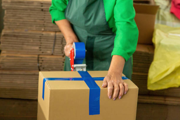 istock Woman in warehouse worker uniform packing cardboard box to delivery. 1333225310