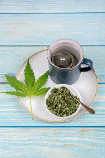 cannabis tea with cup and tea strainer - cannabis, marijuana - photography sign table ganja imagens e fotografias de stock