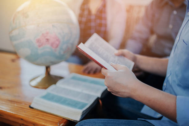 istock Christian fellowship group  in home with reading bible and pray over blurred world globe on wooden table 1333230219
