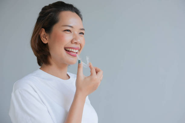 nahaufnahme junge asiatische schöne frau lächelt mit dental aligner retainer tool (unsichtbar) auf grauem hintergrund für schönes zahnbehandlungskurskonzept - zahnschiene stock-fotos und bilder