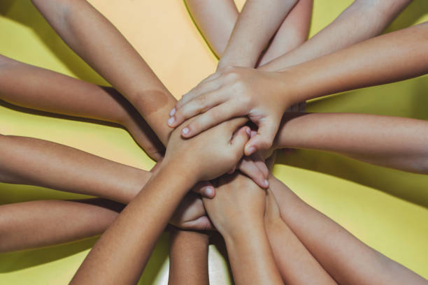 istock Children joining hands over yellow background 1333231453