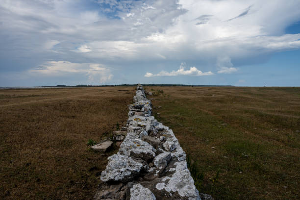 Closeup of a boundary wall made of stones and concrete in the countryside with blue sky and clouds on background. Verona province, Veneto, Italy, Europe.