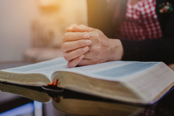 istock Close up of woman's hands praying on open bible 1333231890