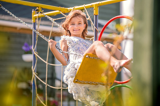 Laughing child girl on a swing at the playground
