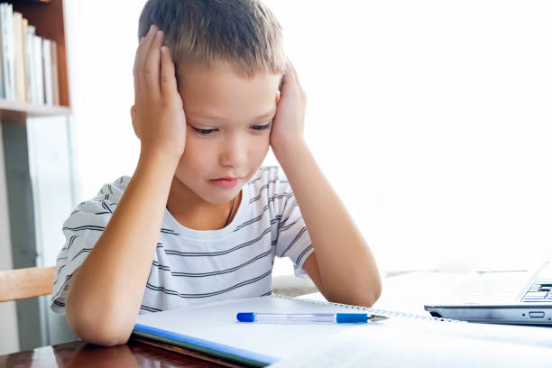 istock Distance learning online education. Schoolboy boy studies at home with laptop and does school homework. Training books and notebooks on table 1333233643