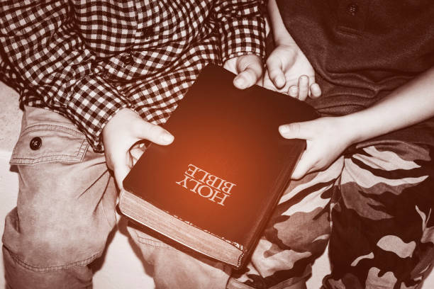 two boys holding red bible together, black and white tone stock photo