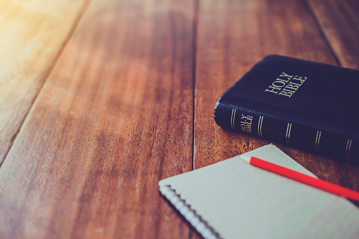 Santa Biblia con libro de notas y lápiz sobre mesa de madera contra la luz del sol de la mañana para la devoción cristiana, espacio de copia photo