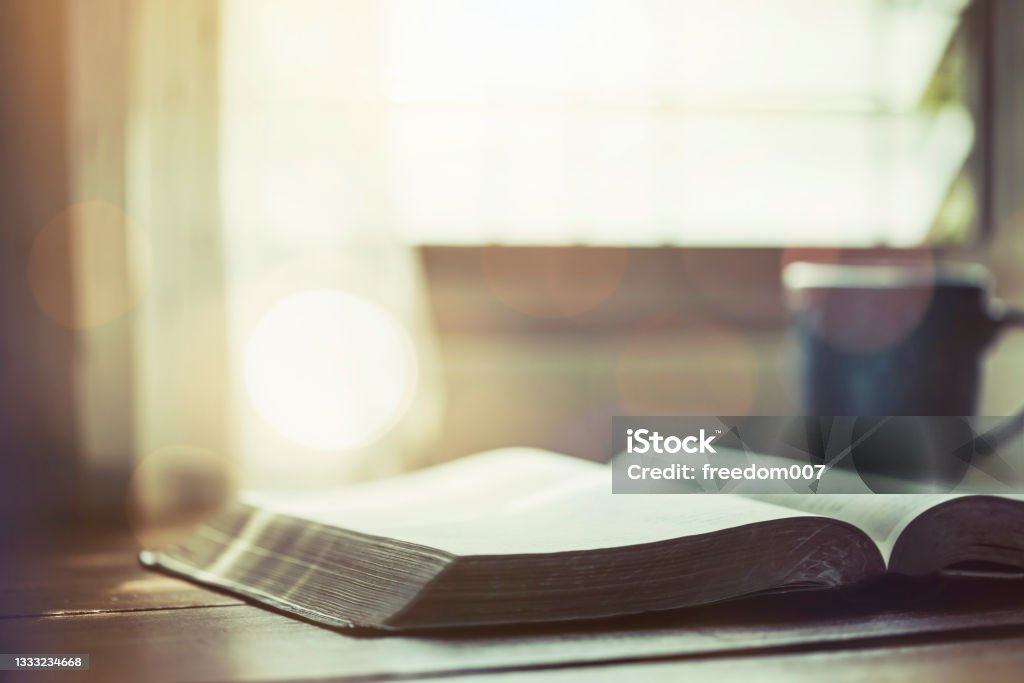 open bible with a coffee cup on wooden table near window, morning devotion concept Bible Stock Photo