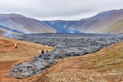 Reykjanes, Iceland - July 13, 2021: Tourists in the Natthagi valley walk on recently cooled lava from the Fagradalsfjall Volcano in southwestern Iceland.