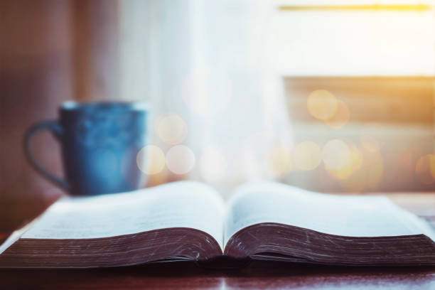 istock open bible with a coffee cup on wooden table near window, morning devotion concept 1333234907