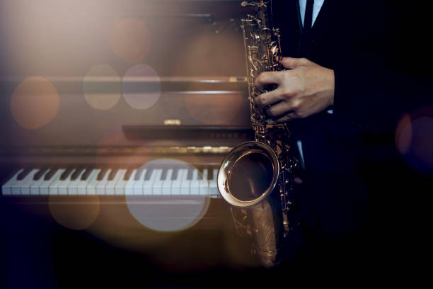 istock musician plays alto saxophone over piano with Bokeh light  background 1333236464