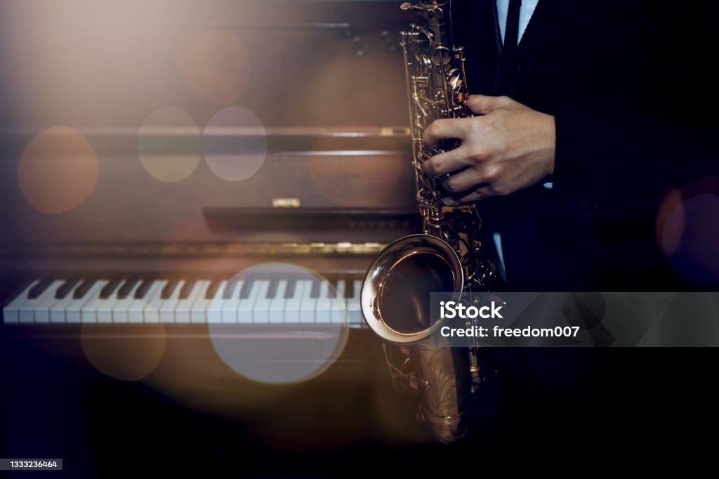 musician plays alto saxophone over piano with Bokeh light  background Saxophone Stock Photo