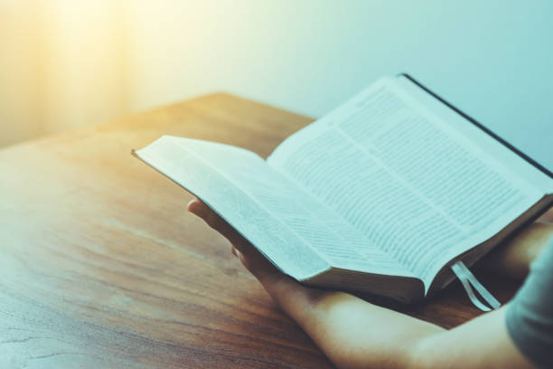 istock A man holding and read the bible on a wood table with window  light, an open bible with blurred page 1333237347
