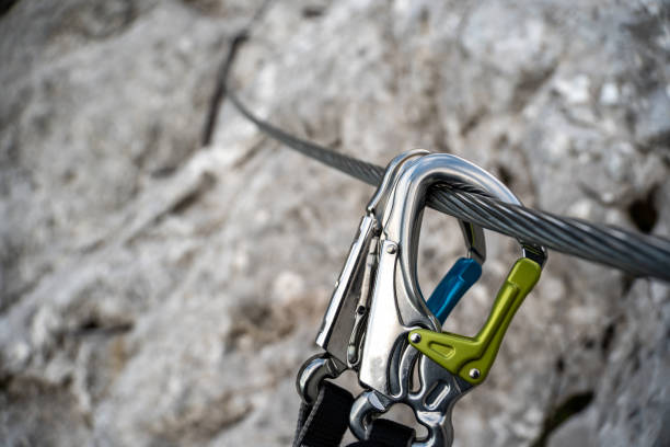 화려한 카라비너 후크가 달린 비아 페라타 세트는 바위 산의 와이어 로프에 걸려 있습니다. - 등산장비 뉴스 사진 이미지