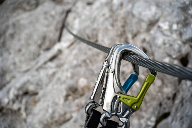 Via ferrata set with colorful carabiner hook hangs on a wire rope on a rocky mountain. Via ferrata set with colorful carabiner hook hangs on a wire rope on a rocky mountain. carabiner stock pictures, royalty-free photos & images