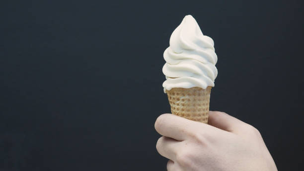 istock Hand is holding Soft serve ice cream cone with black back ground. 1333243801