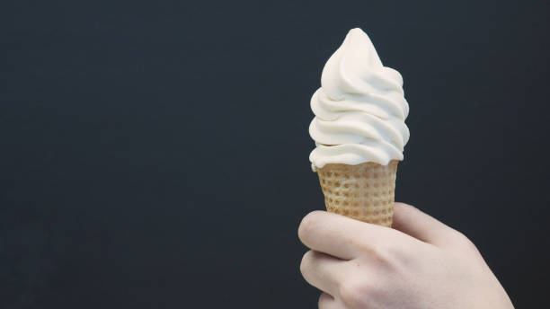 istock Hand is holding Soft serve ice cream cone with black back ground. 1333243817