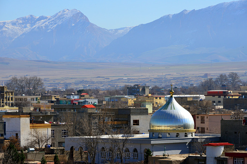 Mazar-i-Sharif, Balkh province, Afghanistan: mosque with silver dome, city rooftops and mountains in the background.