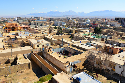 Mazar-i-Sharif, Balkh province, Afghanistan: city skyline - traditional adobe houses with backyards surrounded by tall walls -  Hindu Kush mountains in the background. Mazar-e-Sharif is the fourth largest city in Afghanistan.  The city is a major tourist attraction due to its fabulous Muslim and Hellenistic archaeological sites.